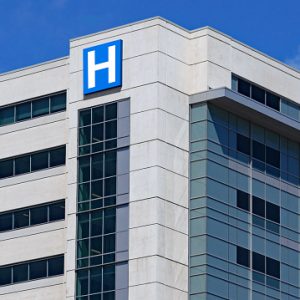 large modern building with blue letter H sign for hospital